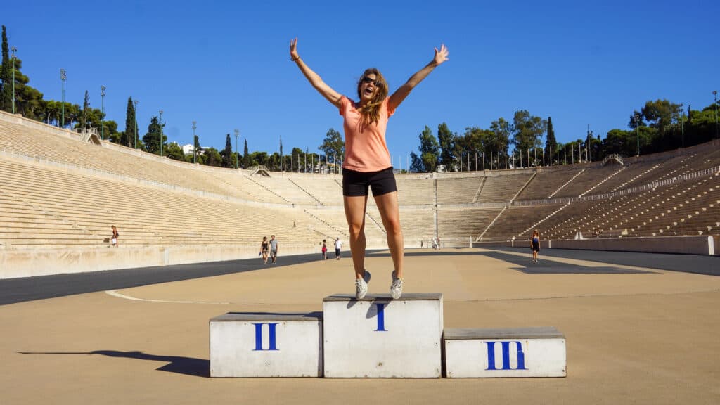 girl standing on podium at olympic stadium in Athens - book 2021 travel now