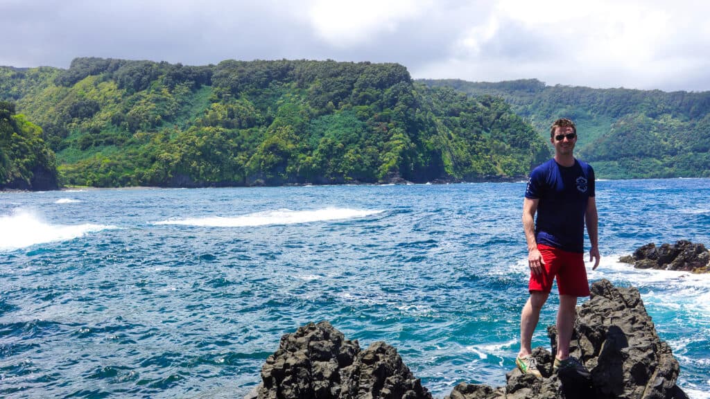man standing on rock -girl in front of surfboards- ultimate guide to road to Hana