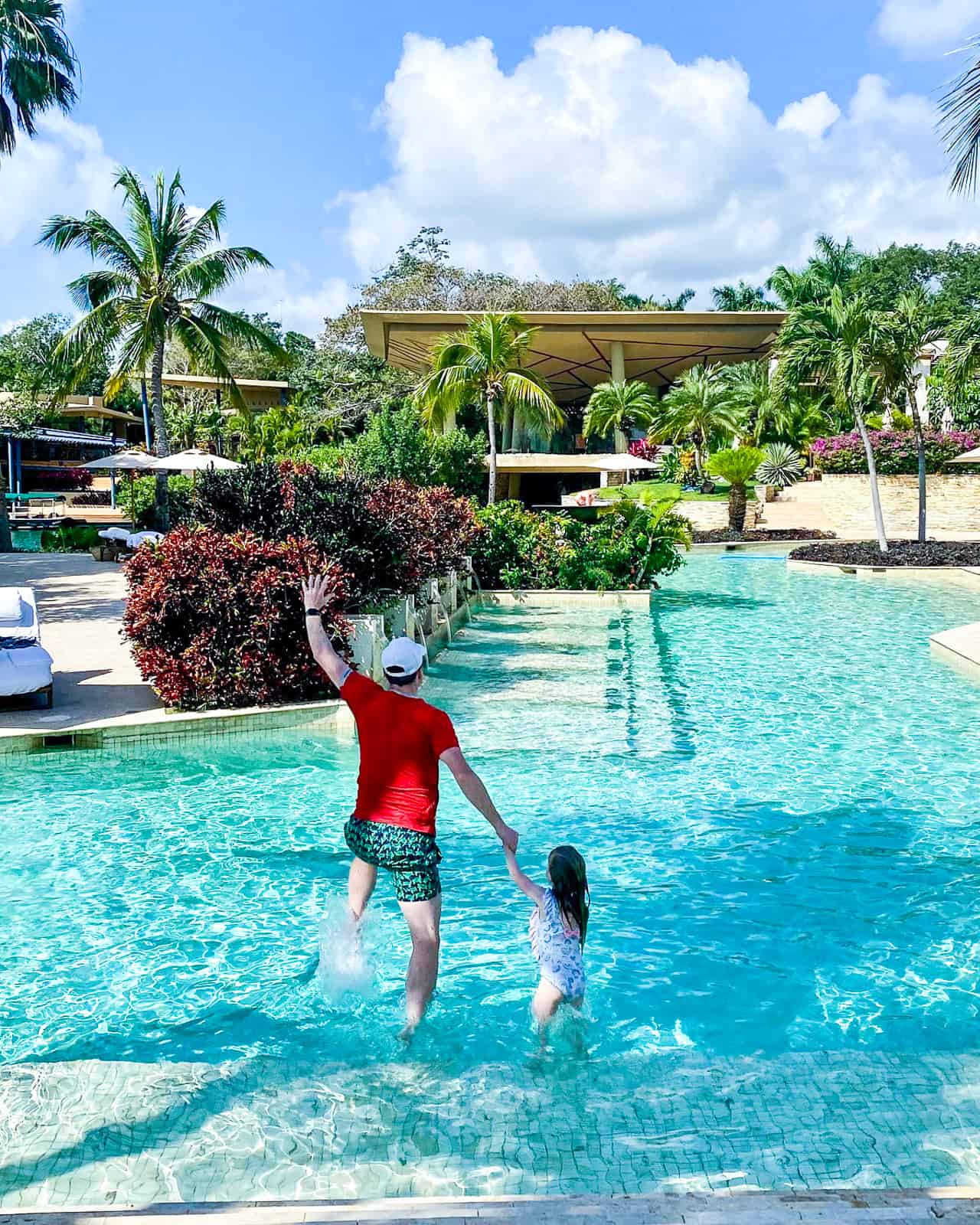 dad and daughter jumping into pool rosewood mayakoba luxury family resort