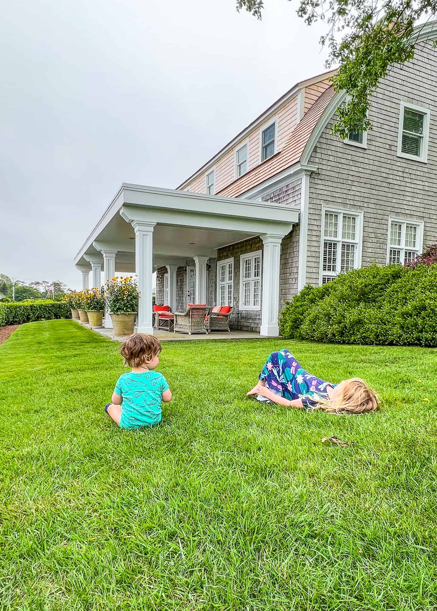 two kids laying in grass outside hotel room - cape cod family vacation