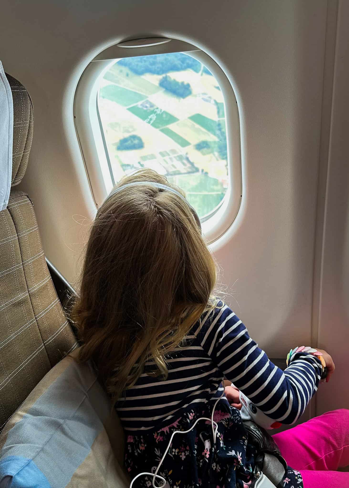 girl looking out window on airplane