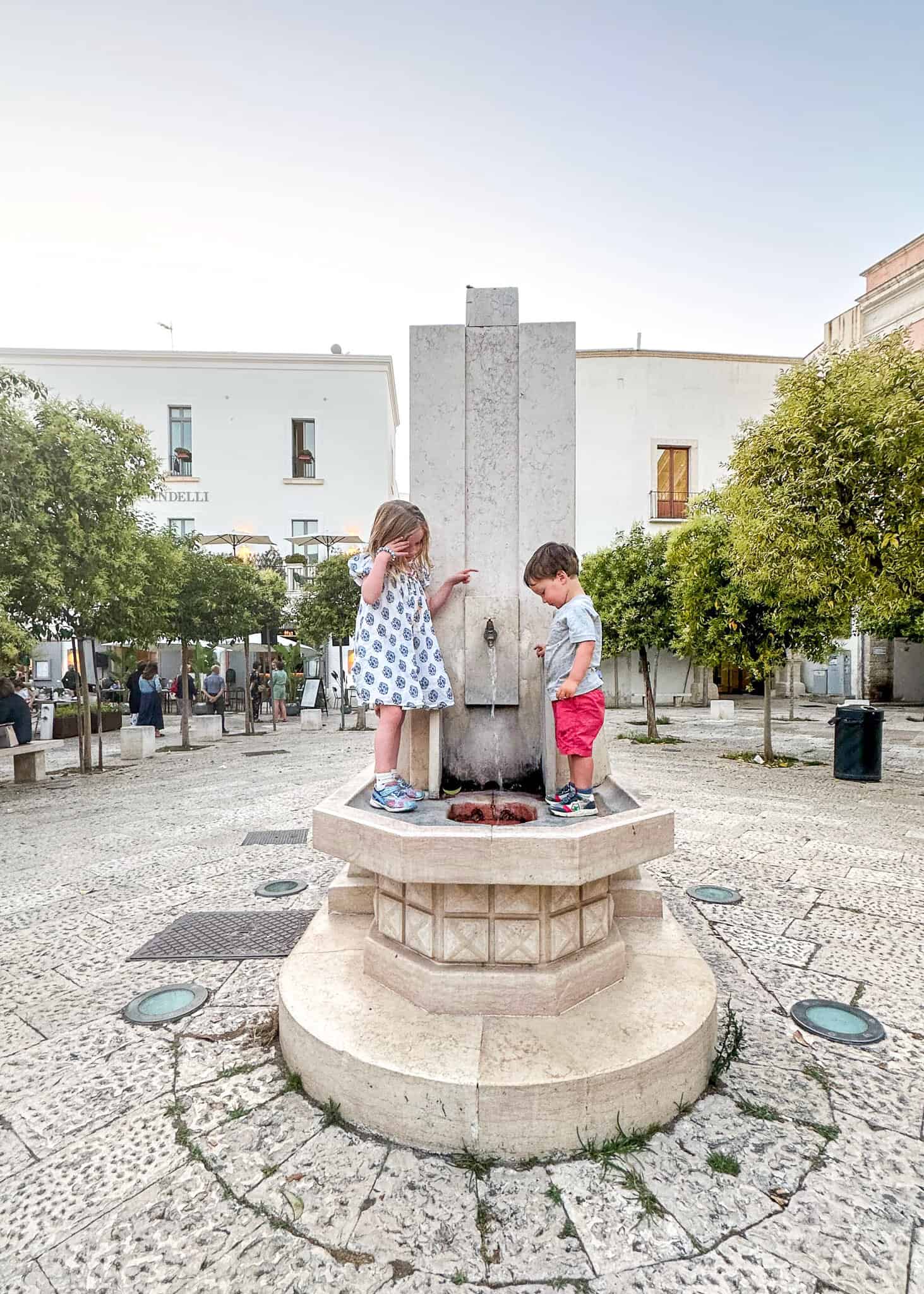 kids exploring monopoly standing on a fountain