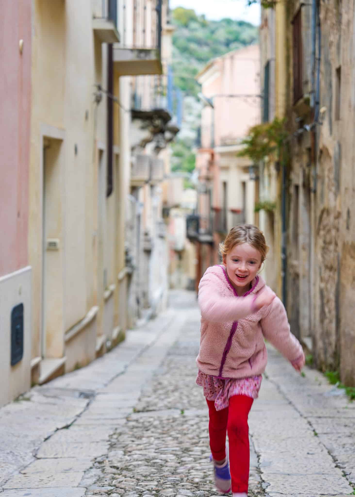 girl running through streets in ragusa, compass roam